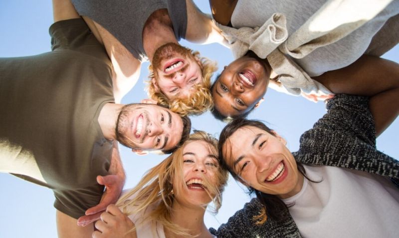 Grupo de jóvenes sonriendo durante una actividad de team building al aire libre.